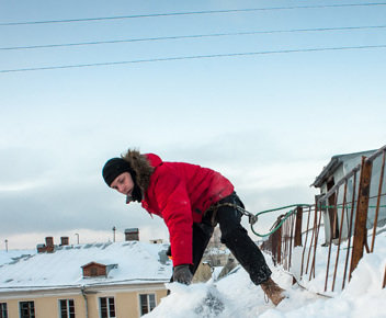 Промышленный альпинист чистит снег с крыши в одном из домов Санкт-Петербурга